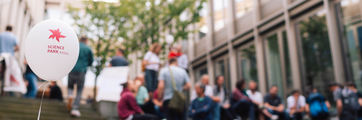 Viele Leute sitzen bei einem Event im sonnigen Innenhof im Unschärfebereich der Kamera