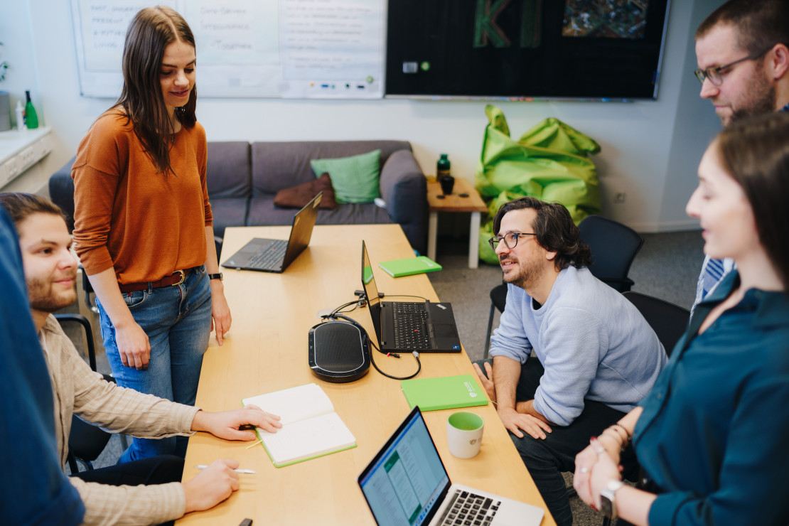 Junge Frauen und Männer eines Start-ups sitzen zusammen in einer Besprechung